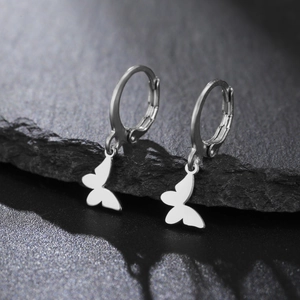 Détail rapproché des boucles d'oreilles créoles en acier argenté avec pendentifs papillon