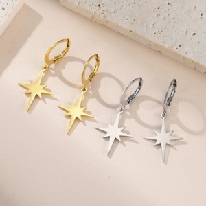 Detail of gold and silver stainless steel star pendant earrings on stone pedestal