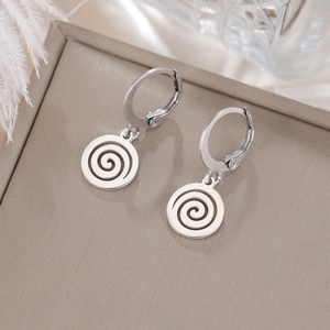Gros plan de boucles d'oreilles créoles en acier avec pendentif spirale sur cuir chic
