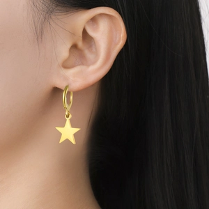 Close-up of a gold star pendant earring on model showing minimalist modern style