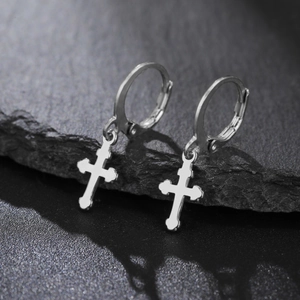 Vue macro de boucles d'oreilles créoles en acier argenté avec pendentifs croix classiques