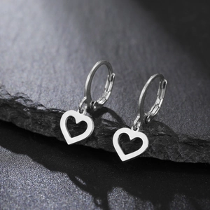 Boucle d'oreille en acier poli avec pendentif cœur sur une pierre texturée sombre