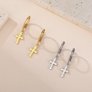Détail de boucles d'oreilles créoles en acier poli or et argent avec pendentifs croix