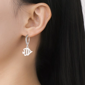 Gros plan d'une boucle d'oreille en acier inoxydable argenté avec pendentif poisson ajouré