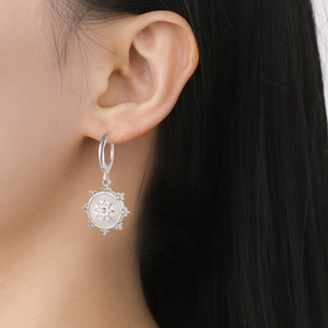 Pendientes de aro plateados con motivo de sol y textura de cuentas en una modelo