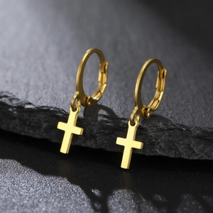 Gros plan de boucles d'oreilles créoles en acier doré avec pendentifs croix sur pierre