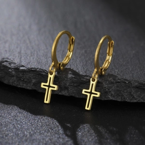 Vue macro de boucles d'oreilles créoles en acier doré avec pendentifs croix évidée