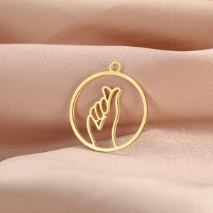 Macro shot of 18K gold hollow round pendant with finger heart gesture for DIY jewelry