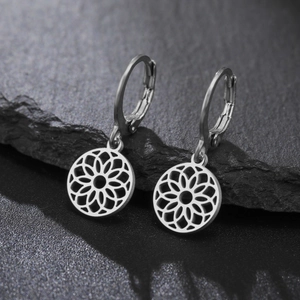 Gros plan détaillé des boucles d'oreilles mandala en argent sur roche noire