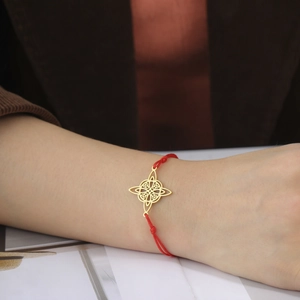 Adjustable red braided rope bracelet featuring a golden Celtic knot charm for women