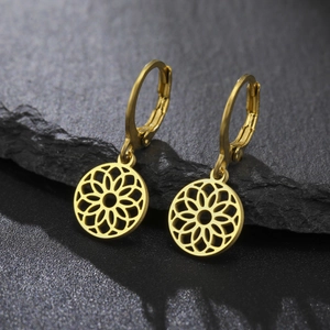 Gros plan sur des boucles d'oreilles dorées géométriques sur fond de pierre noire