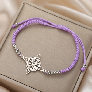Macro detail of purple braided rope bracelet with stainless steel Celtic knot charms