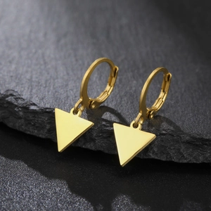 Détail macro de boucles d'oreilles créoles en acier doré avec pendentifs triangulaires