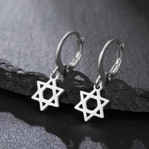 Gros plan sur boucles d'oreilles étoile hexagonale en acier inox sur pierre sombre