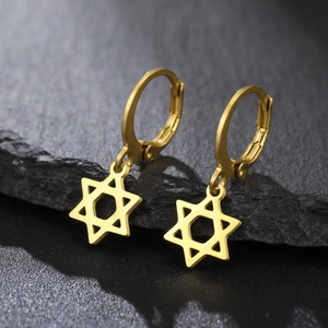 Détail de créoles dorées avec pendentif étoile hexagramme sur fond de pierre foncée