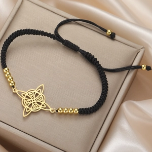 Detail view of black braided bracelet with gold Celtic knot charm on satin background