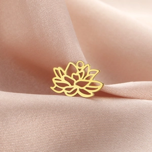 Vue détaillée d'un pendentif lotus doré sur un fond en satin rose doux et soyeux