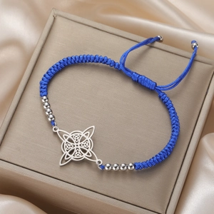 Detail of woven blue rope bracelet with Celtic knot metal charm on satin background