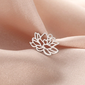Gros plan d'un pendentif lotus argenté évidé posé sur un tissu en soie rose doux