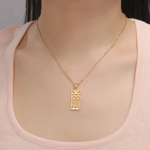 Détail d'un pendentif masque Tiki doré sur une fine chaîne en acier inoxydable