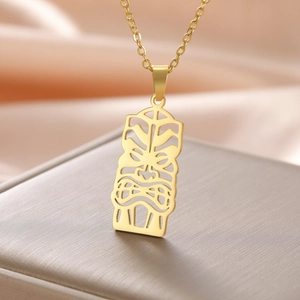 Gros plan détaillé du pendentif masque Tiki doré sur un tissu en soie rose