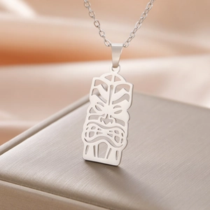Gros plan d'un collier pendentif masque tiki en acier inoxydable sur un coffret cadeau