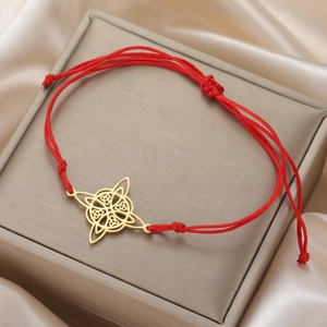 Close-up of golden Celtic knot pendant on red cord bracelet on jewelry box