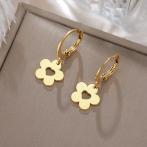 Vue détaillée des boucles d'oreilles fleurs dorées avec motif cœur évidé sur fond gris