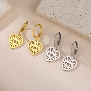 Gros plan de boucles d'oreilles cœur dorées et argentées avec œil ajouré sur pierre