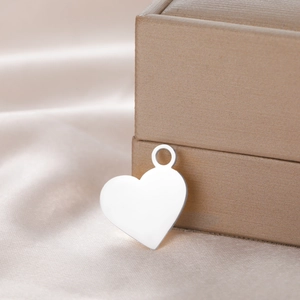 Polished silver heart pendant accessory on elegant champagne satin backdrop