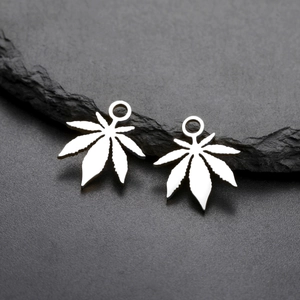 Detailed macro view of silver leaf-shaped stainless steel pendants on a stone surface