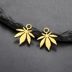 Macro shot of 18K gold plated stainless steel sun leaf pendants on black stone