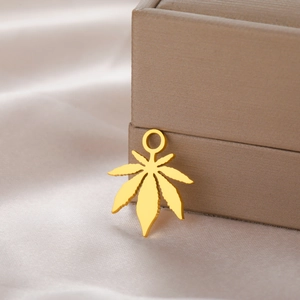 Detailed close-up of a 18K gold-plated stainless steel cannabis leaf pendant on satin cloth