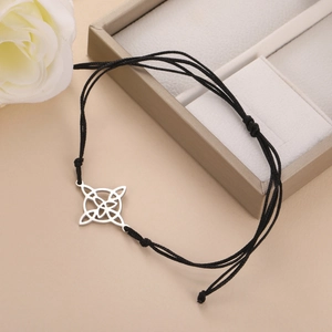 Detail of adjustable black woven bracelet with silver Celtic knot charm on gift box