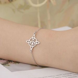 Close-up of a silver stainless steel chain bracelet with a Celtic knot charm on a wrist