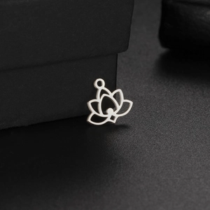 Vue macro d'un pendentif lotus en acier inoxydable argenté sur une surface noire texturée