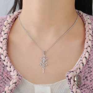 Minimalist stainless steel lotus and unalome pendant necklace on a pink tweed jacket