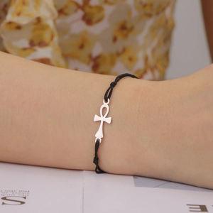 Minimalist silver Ankh cross pendant bracelet with black woven cord on female wrist