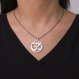 Close-up of a silver Lotus OM pendant necklace worn by a model on a black V-neck top