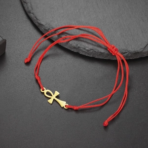 Detail of red cord bracelet with golden Ankh cross pendant and adjustable knot