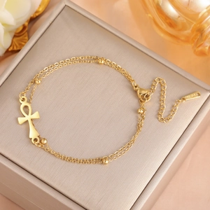 Macro detail of gold Ankh pendant and lobster clasp on a double-layer stainless steel chain