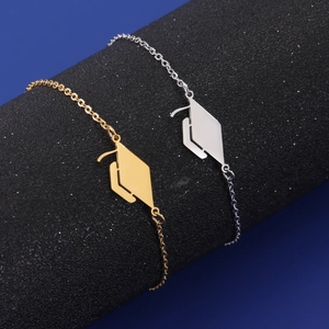 Close-up of polished stainless steel mortarboard pendants on delicate bracelets