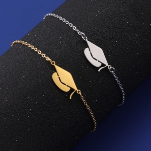Detail view of gold and silver graduation cap charms on stainless steel chain bracelets