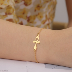 Close-up of gold Ankh cross pendant on a minimalist stainless steel chain bracelet