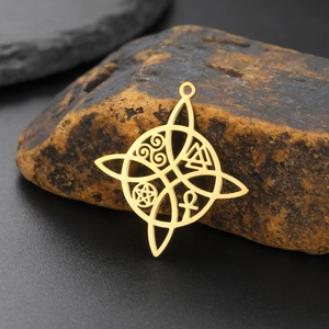 Detalle macro del colgante nudo de bruja dorado con símbolos de Ankh y Triskel