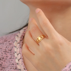 Dettaglio di un anello traforato dorato con tartaruga e stella marina sulla mano