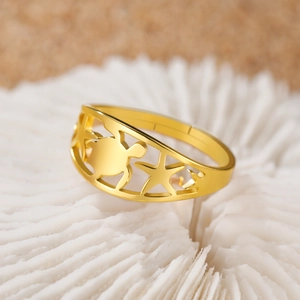 Macro di anello in acciaio inossidabile dorato con tartaruga e stella marina su corallo