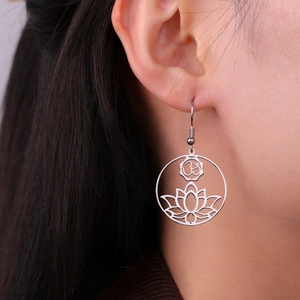 Stainless steel lotus flower and Om symbol dangle earrings shown on a model's ear
