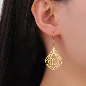 Detail of gold lotus cutout teardrop earrings shown on a model for dangle effect