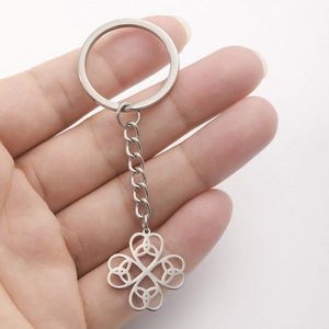 Close-up of a silver stainless steel four-leaf clover keychain with Celtic knot patterns